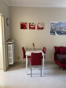 uma sala de jantar com uma mesa branca e cadeiras vermelhas em Apartment "Borgo Olivetti" em Ivrea