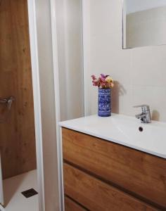 un baño con lavabo con un jarrón de flores. en Casa Rural 643km en Villatuerta