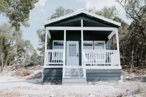 a small shack with a white door in the sand at Nest - Texas Tiny House with a Big View in Spring Branch