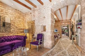 a living room with a purple couch and a stone wall at Ca´n Pere in Alcudia