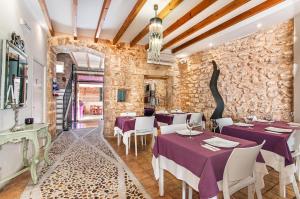 a restaurant with purple tables and chairs and a stone wall at Ca´n Pere in Alcudia