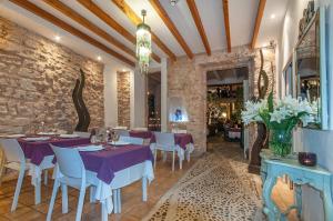 a restaurant with purple tables and chairs and a stone wall at Ca´n Pere in Alcudia