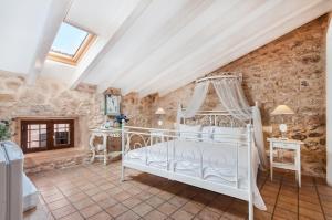 a bedroom with a white bed in a stone wall at Ca´n Pere in Alcudia