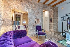 a living room with a purple couch and a stone wall at Ca´n Pere in Alcudia