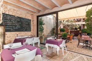 a restaurant with purple tables and chairs and a chalkboard at Ca´n Pere in Alcudia
