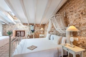 a bedroom with a white bed and a stone wall at Ca´n Pere in Alcudia