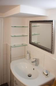een witte badkamer met een wastafel en een spiegel bij Ferienwohnung Auszeit Perle des Ohmtales in Homberg an der Ohm