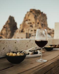 a glass of wine sitting on a table with a plate of food at Juno Cappadocia Adults Only in Uchisar