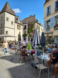 een groep mensen die aan tafels met paraplu's zitten bij La Cascade et des Halles in Dijon