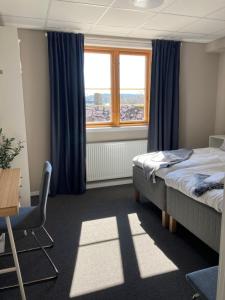 a bedroom with a bed and a window with blue curtains at Morlanda B&B in Ellös