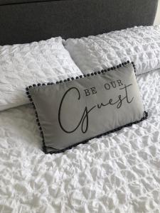 a bed with a pillow with the words be our guest at Charming Apartment in Ashley Cross in Parkstone