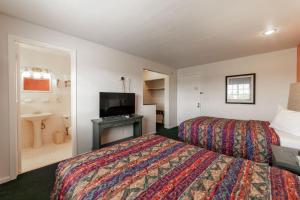 a hotel room with two beds and a television at Captain's Table Hotel by Everglades Adventures in Everglades City