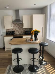 a kitchen with three bar stools and a counter top at Charming Apartment in Ashley Cross in Parkstone