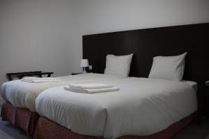 Una cama blanca grande con toallas blancas. en Casa dos Remendos - Alojamento Local en Termas de Sao Pedro do Sul
