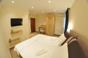 1 dormitorio con 1 cama blanca grande y TV en Η ΦΛΩΚΑΤΗ en Spercheiada