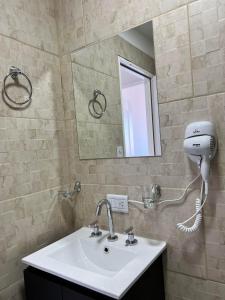 ein Badezimmer mit einem Waschbecken, einem Spiegel und einem Haartrockner in der Unterkunft APART trelew 3 in Trelew