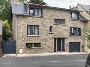 a brick house with black windows on a street at GINGER in Cancale