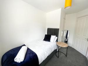 a bedroom with a bed with white sheets and a table at Starview Apartment - Hawthorne in Colchester