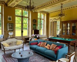 a living room with a blue couch and a pool table at Château de Contay Guesthouse - 1753 in Contay