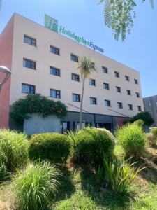 ein Hotel mit einer Palme vor einem Gebäude in der Unterkunft Holiday Inn Express - Marseille Airport, an IHG Hotel in Vitrolles