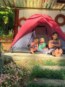 une femme et deux enfants assis dans une tente dans l'établissement Ready Camp e Suítes da Cachoeira, à Abraão
