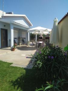 a house with a patio with an umbrella and some flowers at EFI APARTMENTS in Fanari