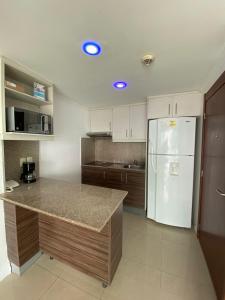 a kitchen with a white refrigerator and wooden cabinets at Ecusuites Riverfront One Vista al Río Jacuzzi Hidro in Guayaquil