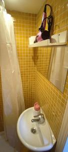 uma casa de banho com um lavatório e uma parede em azulejos amarelos em Mini Loft en Calle Amparo em Madri