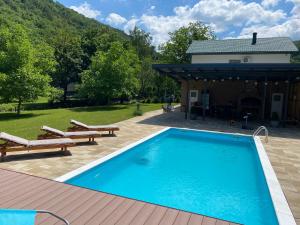 une piscine avec deux bancs et une maison dans l'établissement Soko holiday home Bihac, à Bihać