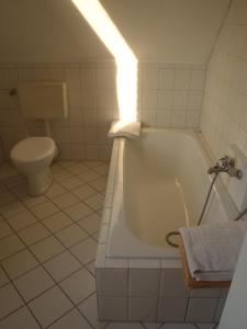 La salle de bains blanche est pourvue d'une baignoire et de toilettes. dans l'établissement Triton II, à Hohwacht