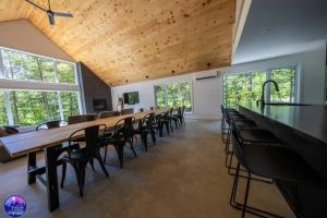 Habitación grande con una larga fila de mesas y sillas. en Chalet Forestria - SPA- Billard- Ski, en Mansonville