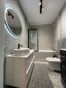 a bathroom with a sink and a tub and a mirror at Misvest Porto Łeba Nadmorska 33 in Łeba