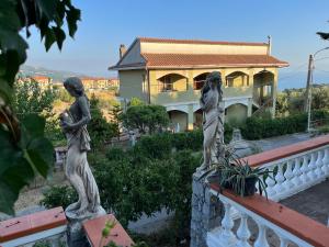 dos estatuas de mujeres de pie en una barandilla frente a una casa en Villa delle Muse da Imma, en Palinuro