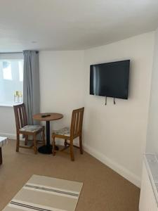 een woonkamer met een tafel en een tv aan de muur bij Harbour Apartment in Barmouth