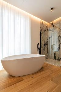 a bathroom with a large white bath tub on a wooden floor at Unico Relais in Naples