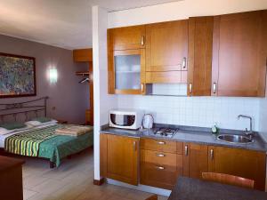 Eurobeach Residence في كافالّينو تريبورتي: مطبخ مع مغسلة وسرير في غرفة