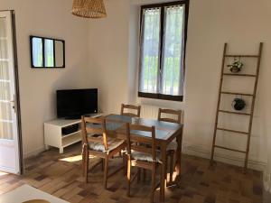 jadalnia ze stołem, krzesłami i telewizorem w obiekcie Petite maison avec terrasse w mieście Jurançon