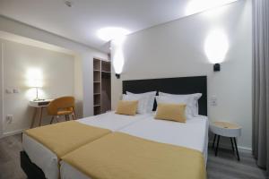 een slaapkamer met een groot wit bed met gele lakens bij Casa do Largo in Termas de Sao Pedro do Sul