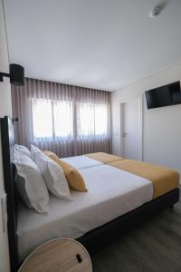 una camera da letto con un letto grande con lenzuola e cuscini bianchi di Casa do Largo a Termas de São Pedro do Sul Altre 45 foto