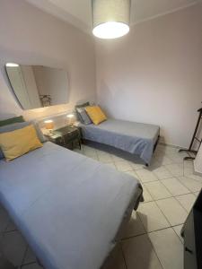 two beds in a small room with a mirror at Appartamento IL CUSCINO DELLA SUOCERA in Foiano della Chiana