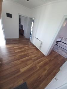 una sala de estar vacía con suelo de madera y paredes blancas en Vila Dervish ÇELA - MOKER, en Pogradec