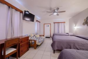 a bedroom with two beds and a desk and a tv at Holiday Hotel in San Pedro