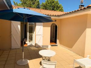 stół i krzesła z niebieskim parasolem na patio w obiekcie Villa de 4 chambres avec piscine privee jardin clos et wifi a Andernos les Bains a 2 km de la plage w mieście Andernos-les-Bains