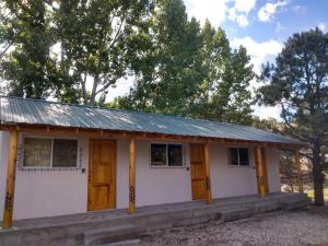 a small white house with a tin roof at Cabaña La Camelia in Creel
