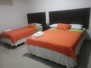 2 camas con sábanas naranjas y verdes en una habitación en Departamento Suite Ciudad del Mar, en Manta