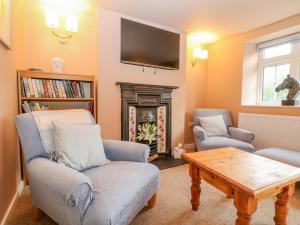 a living room with two chairs and a fireplace at Halfpenny Cottage in Lechlade