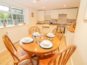 cocina y comedor con mesa de madera y sillas en Halfpenny Cottage, en Lechlade