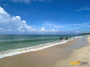 a group of people walking on the beach at Desaru Arcadia Villa with Pool Table, Outdoor BBQ, Indoor Steamboat by Beestay in Kangkar Chemaran