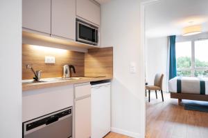 a kitchen with white cabinets and a bed in a room at Residhome Chartres in Chartres