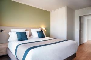 a bedroom with a large white bed with blue pillows at Residhome Chartres in Chartres